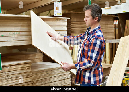 Uomo sceglie e acquista il legno compensato in un supermercato di costruzione Foto Stock