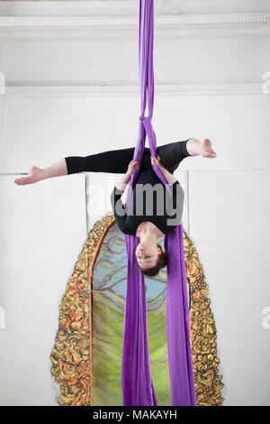 Giovane donna attraente è appeso a testa in giù eseguire un esercizio sull'antenna la seta Foto Stock
