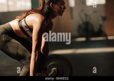 Donna con corpo muscolare che solleva pesi pesanti in palestra. modello di fitness con esercizio di sollevamento pesi in palestra. Foto Stock