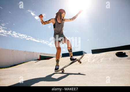 Skater femmina lo skateboard a skate park. Le donne di fare trucchi su skateboard. Foto Stock