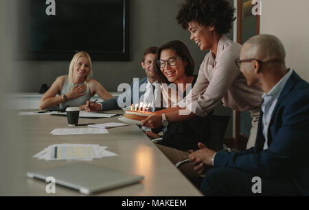 Un gruppo di uomini di affari che celebra una femmina di executive il compleanno nella sala conferenza. Team collega festeggia il compleanno in ufficio durante una meetin Foto Stock