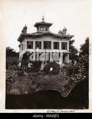 Verticale, fotografia in bianco e nero che mostra la W. H. D. Barnard residence, situato all'angolo di Meramec Street e Virginia Avenue. La casa a 2 piani dispone di una piccola camera nella torre al centro del tetto e ornati di camini di mattoni in corrispondenza dei quattro angoli. In legno rivestimento di panpepato decora il portico e la linea del tetto. Boccole e altre Fogliame circondano la casa. Un giardiniere può essere visto scavando nel giardino sul davanti e una donna si siede sul portico. La fotografia è stata scattata nel 1878, ma la stampa è stato probabilmente costruito nel periodo compreso tra il 1940-1962. Vedere il retro della stampa per le note scritte dal dottor William G. Foto Stock