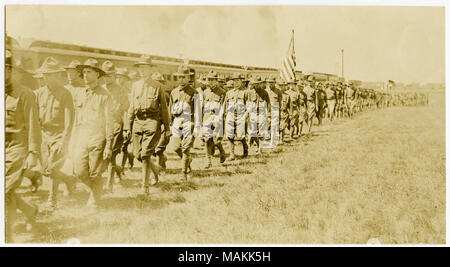 Orizzontale, seppia fotografia che mostra i soldati in uniforme marciando nella formazione attraverso un campo. Un treno può essere visto dietro i soldati. Titolo: soldati che marciano in formazione. . Tra circa 1914 e circa 1918. Michel, Carl Foto Stock