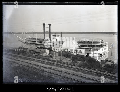 In orizzontale e di fotografia in bianco e nero che mostra il steamboat Helena Ancorata sulle rive di un fiume. Una piccola collezione di edifici in legno sono sulla riva del fiume e due set di binari corrono attraverso il primo piano. Titolo: Steamboat Helena. . Tra 1881 e 1886. Foto Stock