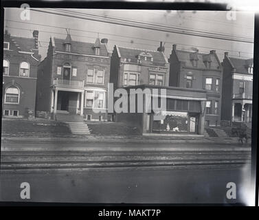 In orizzontale e di fotografia in bianco e nero che mostra una fila di due-storia, single-famiglia case in mattoni, probabilmente in Delmar tra Unione e Kingshighway. La vista è alla ricerca di tutta la strada e i binari tram verso la casa nel centro, che ha attaccato un vetrina al piano terra. Un poster di dimensioni ridotte con uno sfondo luminoso e una croce al centro può essere visto in molte delle finestre, eventualmente una croce rossa bandiera del servizio dato fuori durante la guerra mondiale I. una vista parziale di un cavallo su strada può essere visto a destra. Una nota su una stampa fatta da questo negativo legge 'zonizzazione', che indica che questo phot Foto Stock