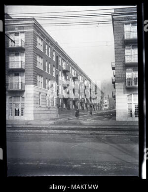 Verticale, fotografia in bianco e nero che mostra una strada tra due edifici di appartamenti. La vista è guardare al di là della strada e mostra i due di quattro piani con balconi. Il primo piano degli edifici sono in pietra, mentre i piani superiori sono in mattoni. Street car rotaie sono visibili in strada. Una nota sulla busta originale recita 'zonizzazione/utilizzare le eccezioni", indicando che questa fotografia potrebbe essere stato utilizzato per dimostrare lo zoning le violazioni o la necessità di ulteriori restrizioni dell'uso. Titolo: una strada non identificato con edifici di appartamenti su ciascun lato. . Tra il 1917 e il 1918. Foto Stock