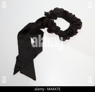 Accessorio di abbigliamento ritiene essere un archetto da collo, in forma di nero di Crespo Seta densamente raccolti su una banda di black grosgrain ribbon, nero con nastro di raso streamers attaccato. Titolo: con archetto di increspato arricciato nero con satin nero Streamers . circa nel 1870. Foto Stock