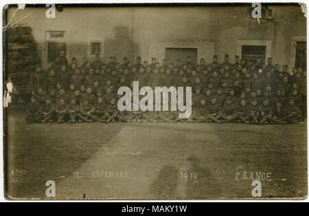 Orizzontale, seppia fotografia postali che mostra un gruppo di uomini in uniforme si sono riuniti al di fuori di un edificio di pietra. Il sole è dietro il fotografo e l'ombra del fotografo e la sua macchina fotografica e altri edifici più trasversale del gruppo. Lungo il fondo in bianco è ' 13 novembre 1918 Francia." Titolo: Personale dell ospedale Base 21 a Rouen, Francia. . Il 13 novembre 1918. Duoioier, Paolo Foto Stock