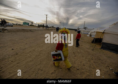 Clown palestinese Alaa Mekdad, 34, cammina alla tendopoli protesta lungo il confine tra Israele e la striscia di Gaza, nella Striscia di Gaza, 02 aprile 2018. Foto: Mohammed Talatene/dpa Foto Stock