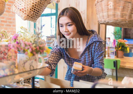 Attraente felice giovane donna asiatica per lo shopping e la selezione dei prodotti dal display in un bel negozio decorata, buona per lo stile di vita di shopping o il Foto Stock