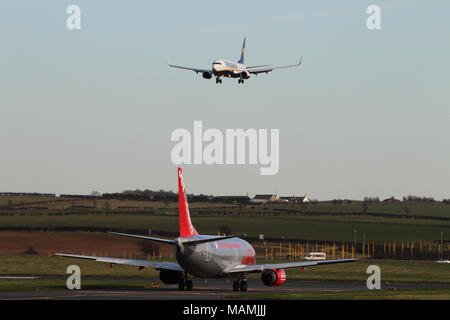 Compagnia aerea rivali - a Ryanair Boeing 737 entra in terreni a Prestwick International Airport, come un Jet2 Boeing 737 (G-CELD) taxi per la partenza. Foto Stock