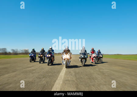 Kiev, Ucraina - 29 Marzo 2017: Foto dinamica di sette motociclisti su moto lungo la lunga strada da qualche parte nel campo sullo splendido cielo blu sullo sfondo. Guardando fiduciosi e libera. Foto Stock