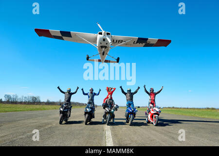 Kiev, Ucraina - 29 Marzo 2017: Piano Bianco è volare sopra i biker seduto sulla moto sport . Gli uomini mantenendo le mani fino, colorati da indossare abbigliamento protettivo e caschi. Sentirsi felice e libera. Foto Stock