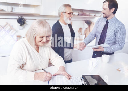 Smilign positiva di età della donna la firma del contratto di assicurazione Foto Stock