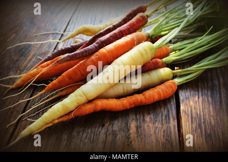 Le carote. Freschi carote colorato scuro su sfondo rustico Foto Stock
