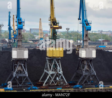 Trasporto di carbone sito incluse tre colorato di blu e giallo gru Foto Stock