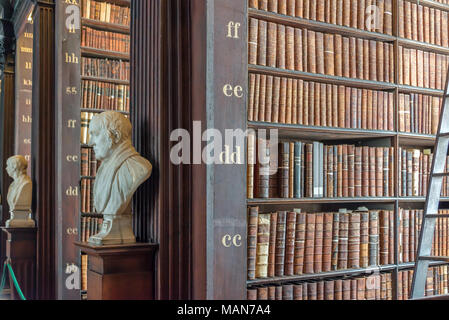 Le statue e le librerie a lungo in camera il Trinity College vecchia libreria a Dublino, Irlanda Foto Stock