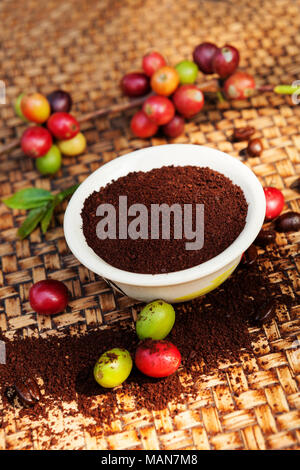 Il caffè macinato, colorato di bacche di caffè e caffè torrefatto beansl sulla superficie di vimini. Sfondo di caffè. Foto Stock