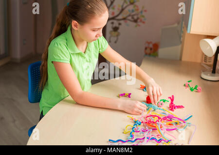 Carino bambina creazione di giocattoli con bastoncini di ciniglia al tavolo. La creatività e il concetto di fatti a mano. Foto Stock