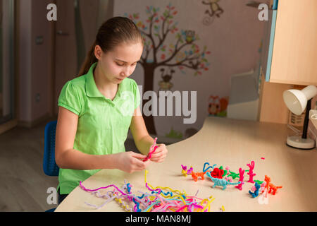 Carino bambina creazione di giocattoli con bastoncini di ciniglia al tavolo. La creatività e il concetto di fatti a mano. Foto Stock