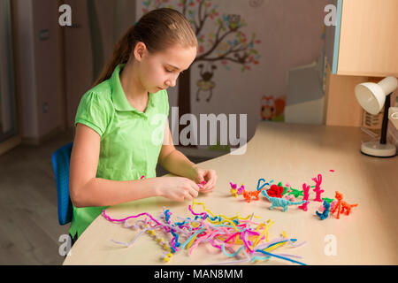 Carino bambina creazione di giocattoli con bastoncini di ciniglia al tavolo. La creatività e il concetto di fatti a mano. Foto Stock