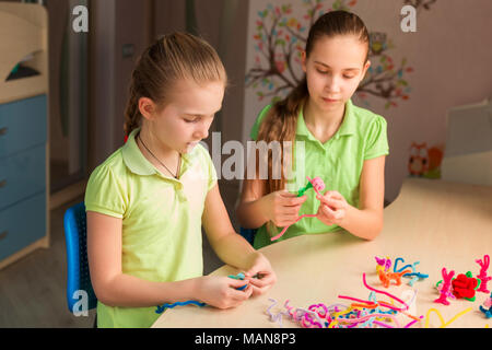 Carino bambine creazione di giocattoli con bastoncini di ciniglia al tavolo. La creatività e il concetto di fatti a mano. Foto Stock