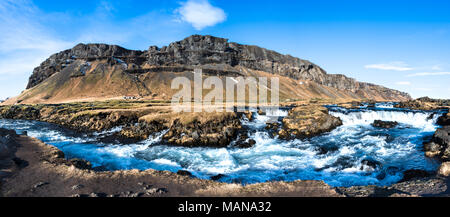Fiume Fossalar rapids in Islanda rurale con montagne, una casa colonica, erba e cielo blu Foto Stock
