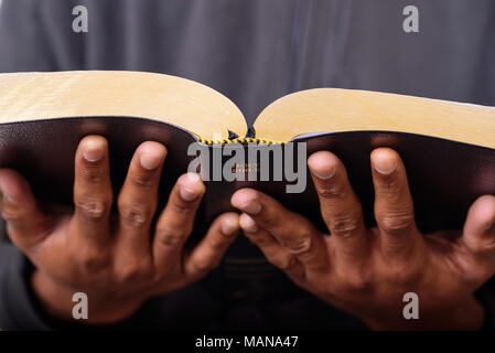 Una vista ravvicinata di un uomo mani tenendo la Sacra Bibbia Foto Stock