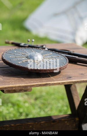 Circolari e schermo metallico su un tavolo di legno: Medievale di armature metalliche e armi. Foto Stock
