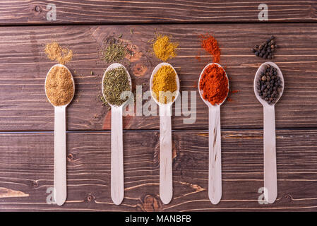 Assortimento di spezie colorate in i cucchiai di legno. Foto Stock