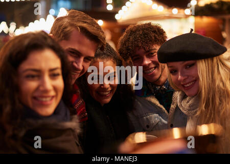 Giovani amici in posa per Selfie Al Mercatino di Natale Foto Stock