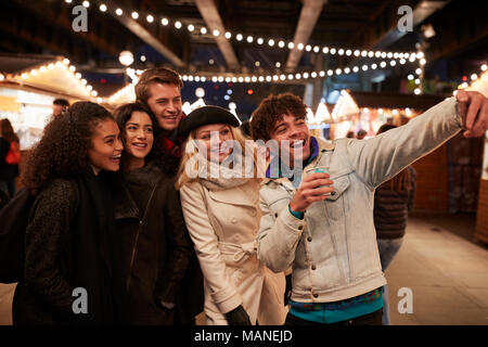 Giovani amici in posa per Selfie Al Mercatino di Natale Foto Stock