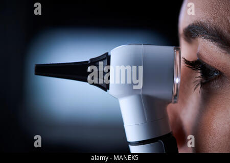 Medico donna utilizzando otoscopio, vista laterale, vicino fino Foto Stock