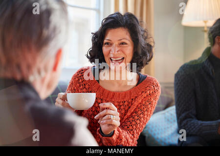 Donna di mezza età incontro con gli amici intorno al tavolo In Coffee Shop Foto Stock