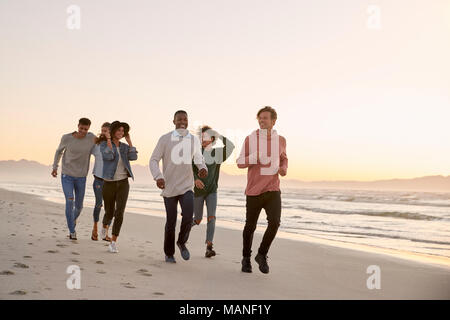 Gruppo di amici a camminare lungo la spiaggia invernale insieme Foto Stock