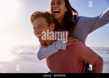 Uomo Donna dando piggyback sulla spiaggia invernale Vacanza Foto Stock