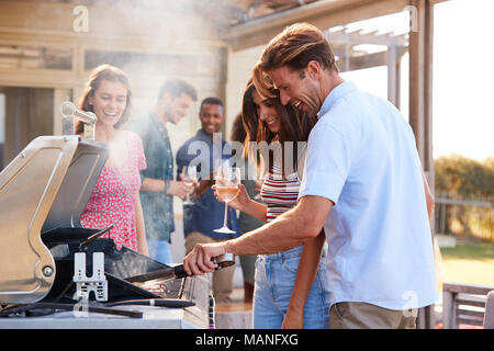 Gruppo di amici gustando un barbecue a casa insieme Foto Stock