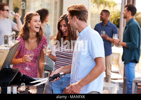 Gruppo di amici gustando un barbecue a casa insieme Foto Stock