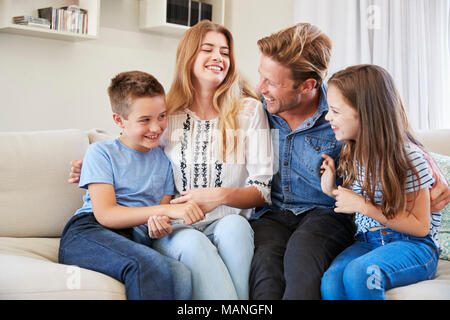 Famiglia sorridente rilassante sul divano di casa insieme Foto Stock