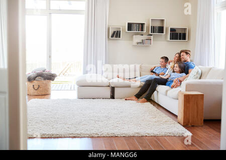 Famiglia seduti sul divano a casa a guardare la TV insieme Foto Stock