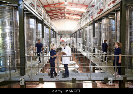 Due persone dello staff parlando sulla passerella in un moderno stabilimento di vinificazione Foto Stock