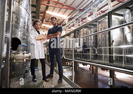 Maschio e femmina di fabbrica del vino i tecnici cercando di fotocamera Foto Stock