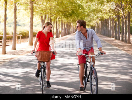 Giovane equitazione biciclette su una strada vuota guardando ogni altro Foto Stock