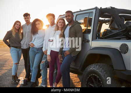 Giovani amici adulti su un viaggio in piedi con la loro jeep Foto Stock