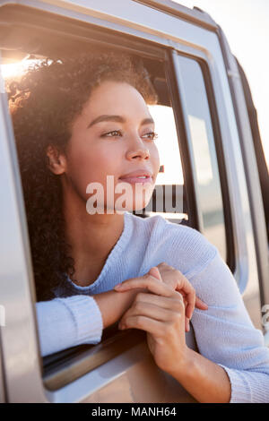 Donna che guarda fuori del passeggero anteriore finestra auto, verticale Foto Stock