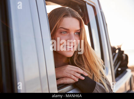 Giovane donna che guarda fuori di aprire la finestra per passeggeri di un automobile Foto Stock