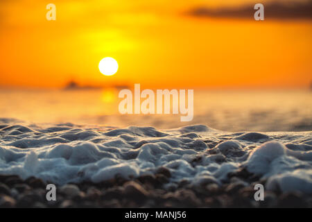 Sunrise luce che risplende su ocean wave Foto Stock