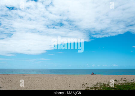 Florianópolis, Brasile. Februry, 2018. Un uomo, una donna e un cane sulla spiaggia, guardando l'orizzonte sul mare. Foto Stock