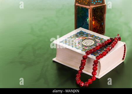 Close up del Libro Sacro del Corano e Rosario rosso e una lanterna su sfondo verde, il Ramadan Kareem Concept Foto Stock