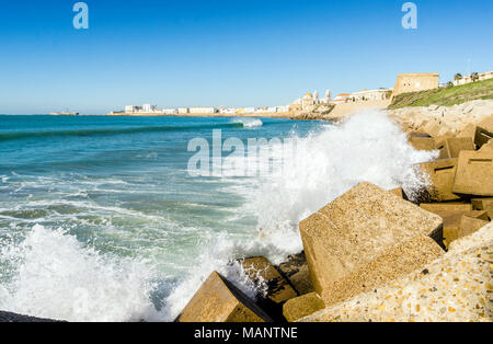 Atlantic di onde che si infrangono sulla riva urbanizzata di vecchi Cadice, Andalusia, Spagna Foto Stock